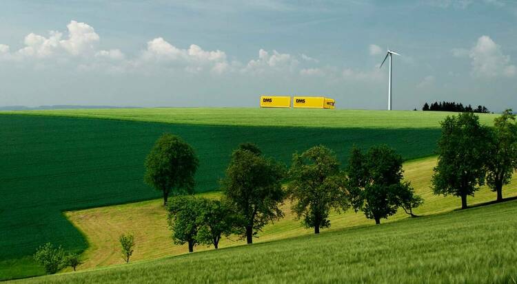 LKW in Landschaft mit Windrad